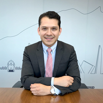 Persona sonriendo con traje en una oficina.