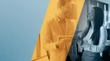 Dos personas conversan y sonríen en una oficina moderna.