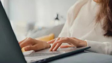 Persona usando una computadora portátil en un espacio cómodo.