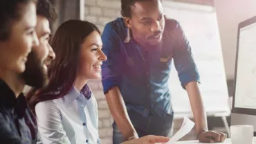 Grupo de personas trabajando en equipo delante de una computadora.