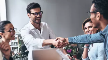 Grupo de personas en una reunión sonrientes y estrechando manos.