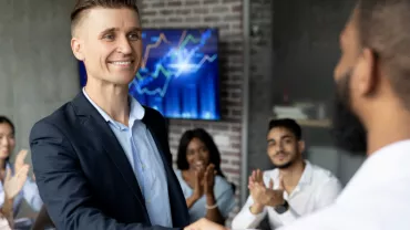 Grupo de personas en una reunión de negocios, aplaudiendo y estrechando manos.