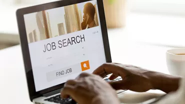 Persona usando laptop con página de búsqueda de empleo.