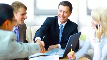 Personas en una reunión de negocios. Dos se dan la mano.