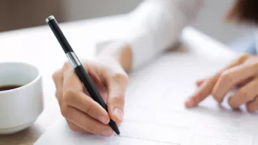 Persona rellenando un formulario con un bolígrafo.