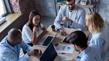 Personas en una reunión de trabajo con laptops y gráficas.