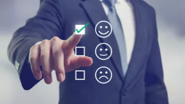 Persona en traje seleccionando cara sonriente en pantalla táctil