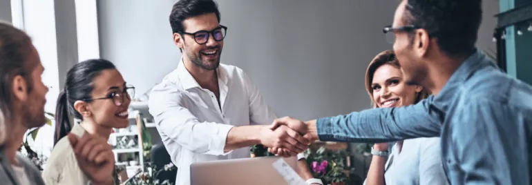 Grupo de personas en una reunión sonrientes y estrechando manos.