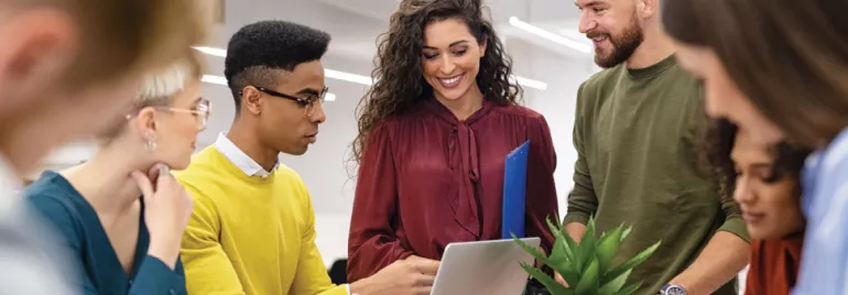 Grupo de personas trabajando en equipo con laptop y plantas.