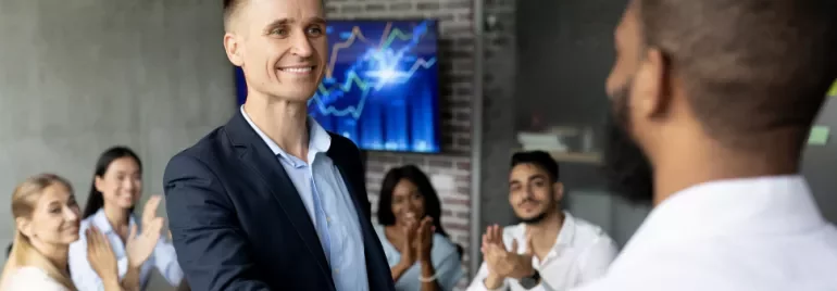 Grupo de personas en una reunión de negocios, aplaudiendo y estrechando manos.
