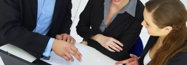 Personas trabajando juntas en una reunión con documentos.