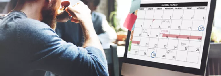 Persona en una oficina revisando un calendario en la computadora.