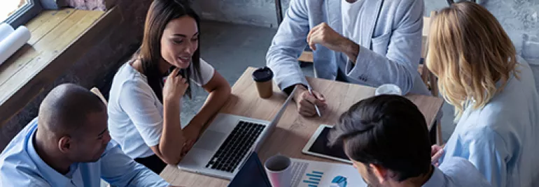 Personas en una reunión de trabajo con laptops y gráficas.