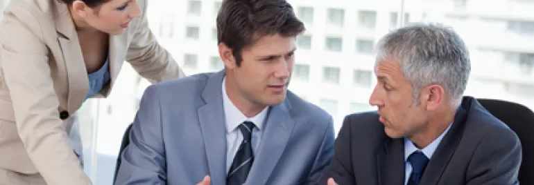 Tres personas discutiendo en una reunión de negocios.