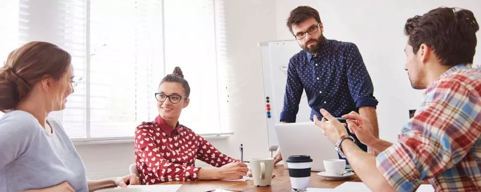 Equipo trabajando en una reunión en una oficina iluminada por el sol.