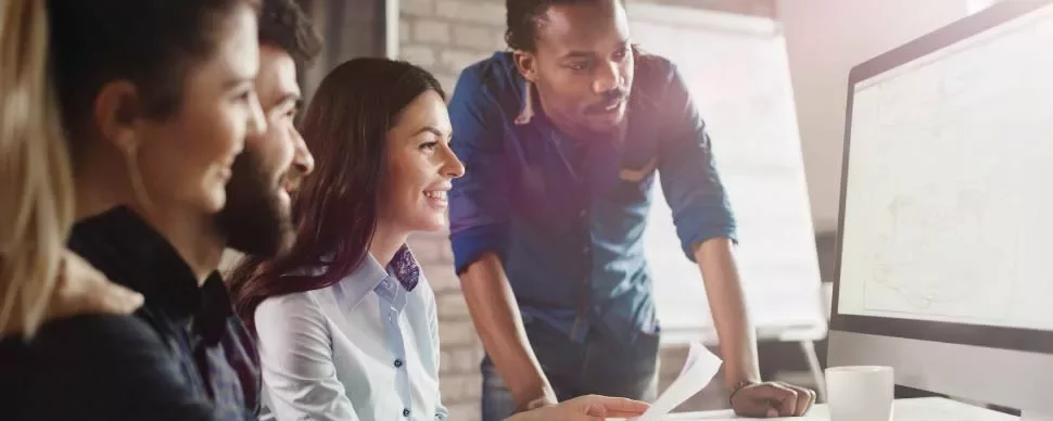 Grupo de personas trabajando en equipo delante de una computadora.