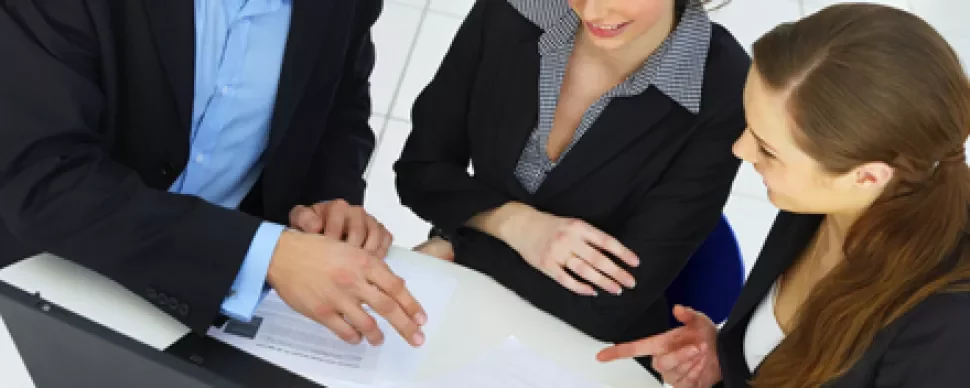 Personas trabajando juntas en una reunión con documentos.