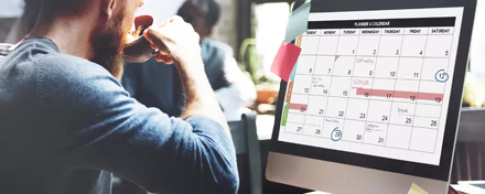 Persona en una oficina revisando un calendario en la computadora.