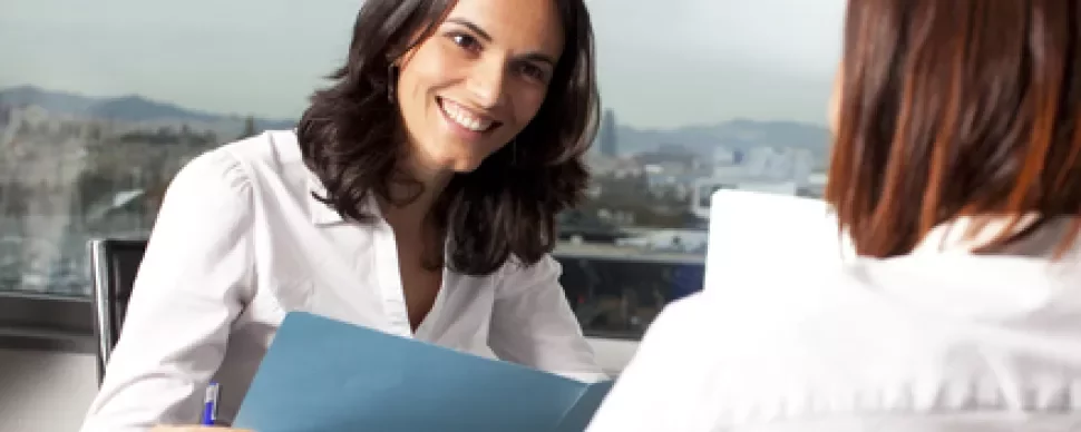 Persona sonriendo con una carpeta azul durante una entrevista.