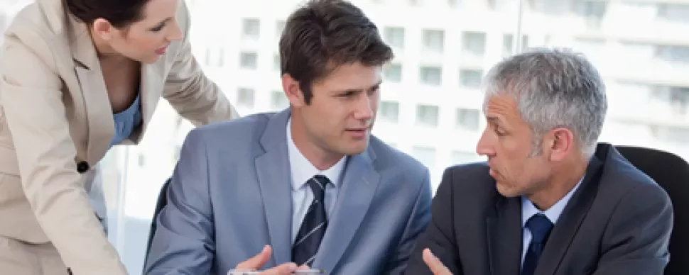 Tres personas discutiendo en una reunión de negocios.
