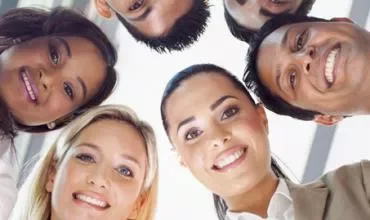Un grupo de personas sonrientes visto desde abajo.
