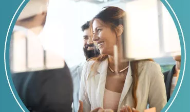 Personas conversando y sonriendo en una reunión de trabajo.