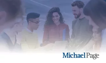 Personas colaborando en una oficina, sonriendo y mirando una laptop.