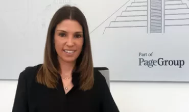 Persona sentada frente a un cartel que dice PageGroup, fondo con dibujo de pirámide.