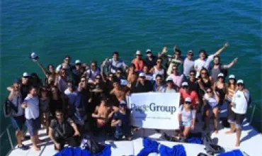 Un grupo de personas en un barco sostiene un cartel sobre el mar.