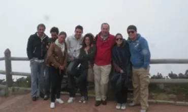 Grupo de personas posando al aire libre con un cielo nublado.