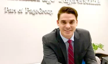 Persona en traje sonriendo en recepción de una oficina de Michael Page.