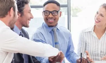 Grupo de personas en una reunión de negocios, sonriendo y conversando.