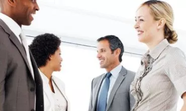 Grupo de personas en una reunión de oficina, conversando y sonriendo.