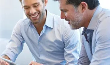 Dos personas revisando un documento juntas, sonriendo.