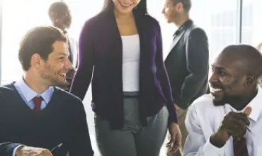 Personas en una reunión de trabajo con una mesa y materiales de oficina.